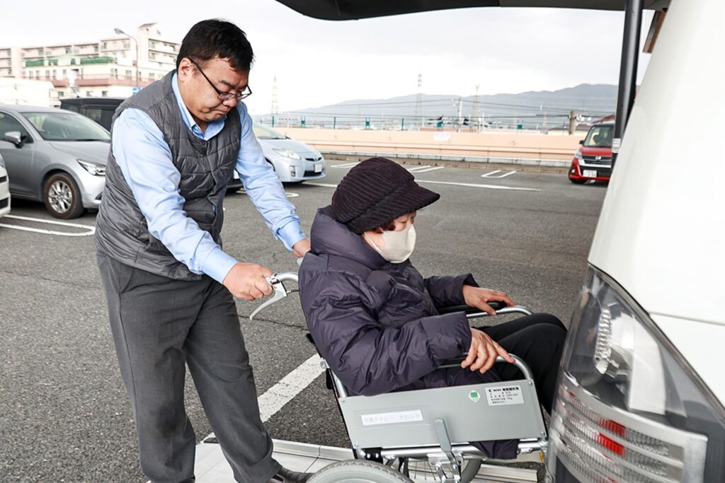 車椅子に乗った女性を車に入れるお手代をしている男性